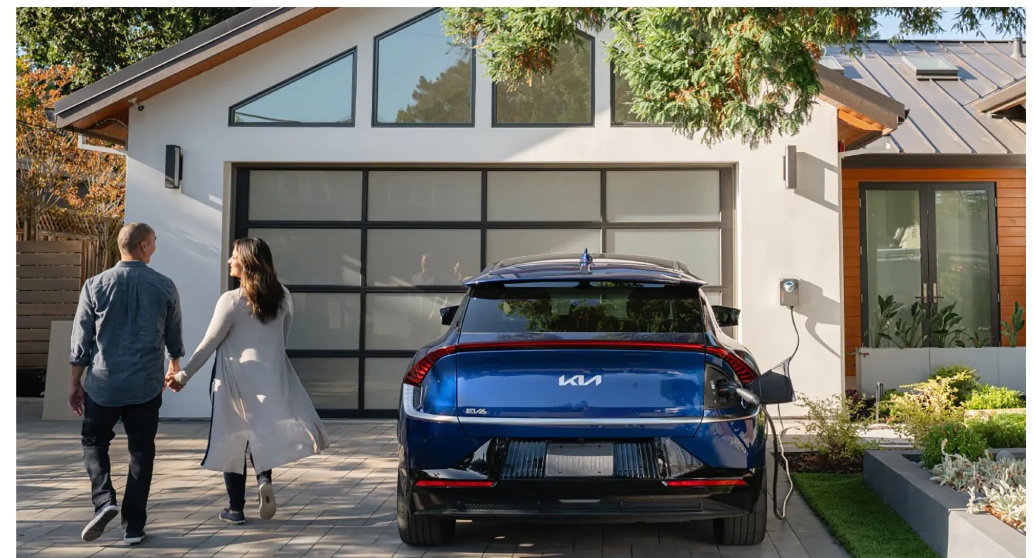 Couple arriving at a short-term rental home with a Kia EV charging in the driveway